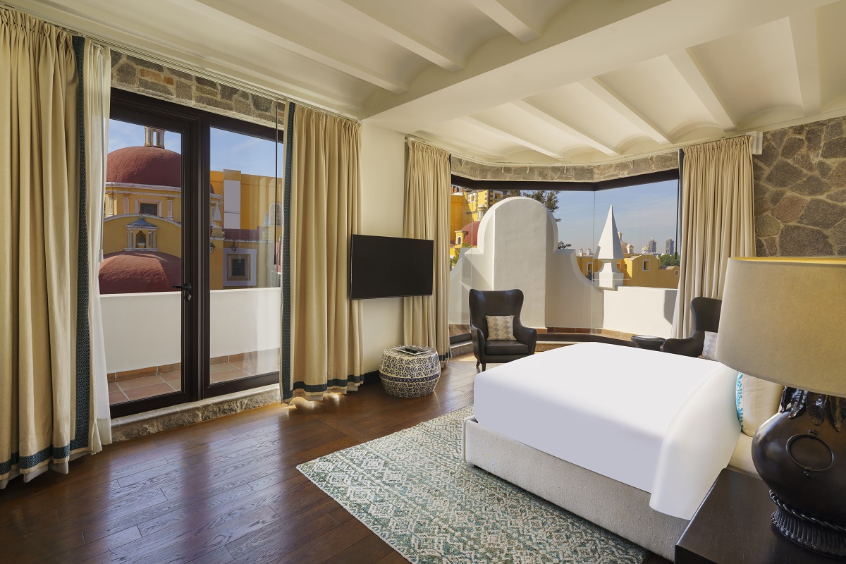 Spacious Banyan Tree Puebla room, bed facing large windows with city view. Elegant decor.